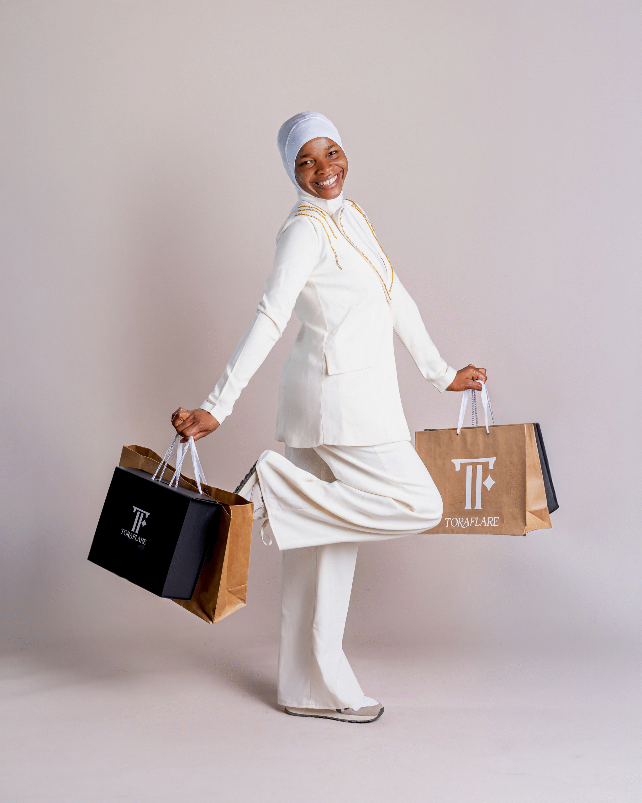 A model in a cream trouser suit carrying Toraflare shopping bags